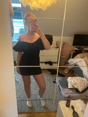 Svart offshoulder volangklänning - Snygg svart kortklänning som man kan ha på två olika sätt både off shoulder och upper på axlarna. Aldrig använd med prislapp kvar