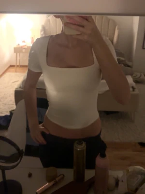 Vit topp med fyrkantig ringning - Snygg vit topp från new yorker med korta ärmar och fyrkantig ringning. Modellen är tight och croppad, perfekt att styla med höga jeans eller kjol. Gjord i mjukt bomullsmaterial som sitter skönt mot kroppen.
