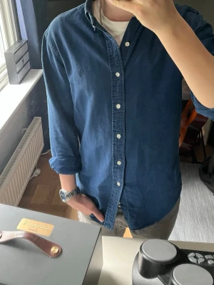 Blå skjorta från Ralph Lauren - I stort sätt oanvänd Ralph Lauren indigo Oxford skjorta. Den är slim fit i storlek S. Skriv om ni önskar fler bilder eller mer information.