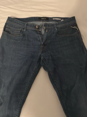 Blå jeans från Replay - Har haft de i ungefär 1 månad Snygga blå jeans från Replay med klassisk femficksdesign och diskreta slitningar. Jeansen har raka ben och detaljerade bakfickor med mönstersöm. Perfekta för en avslappnad och trendig look.