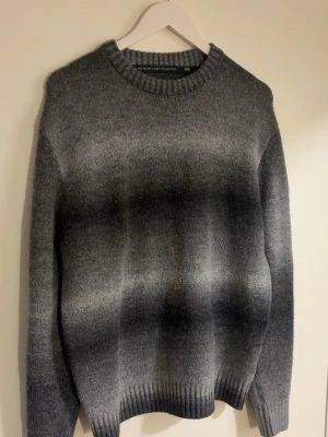Gråmelerad stickad tröja H&M - Snygg stickad tröja från lager 157 i gråmelerat med mjuka övergångar mellan ljusgrått och mörkgrått. Perfekt för kalla dagar eller svala sommar kvällar, och enkel att matcha.