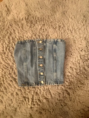 Denim tubtopp med knappar - Snygg ljusblå denim tubtopp med knappar framtill och smockad rygg för extra komfort. Har aldrig använts köpte second men passade inte💕