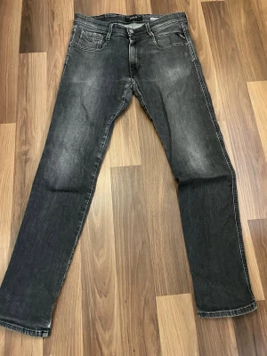 Svarta jeans från Replay 32/32 - Snygga svarta jeans från Replay med smal passform och klassisk femficksdesign. Jeansen har diskreta slitningar framtill och bakfickor med broderad detalj. Perfekta för en trendig och avslappnad look. 32/32