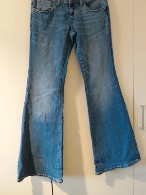 Blå utsvängda jeans från Perfect Jeans - Säljer ett par blå jeans från Perfect Jeans i modell med utsvängda ben. Klassisk femficksdesign och knappgylf. Jeansen har en snygg tvättad look och är tillverkade i denim.