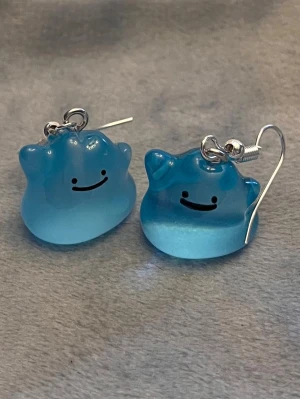 Självlysande Shiny Ditto örhängen Pokémon smycke  - Så gulliga örhängen med Ditto! Berlockerna är ca 1,5 x 1,5 cm. Den är också självlysande och lyser i mörkret.