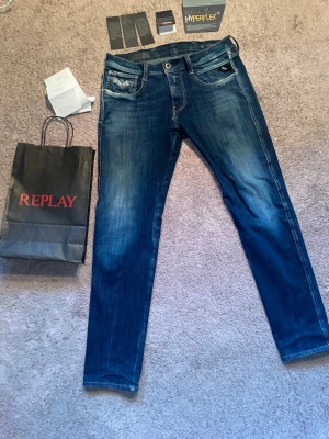 Replay Hyperflex+ slim fit Jeans - W28 L30 Hyperflex slim fit. Snygga blå jeans från Replay med Hyperflex-teknologi som ger extra stretch och komfort. Jeansen har klassisk femficksdesign, smal passform och snygga slitningar framtill. Perfekta för dig som vill ha både stil och rörelsefrihet.
