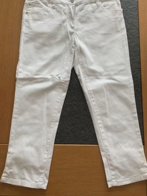 Vita Capri Jeans  - Säljer ett par vita jeans i storlek xs med en fin passform. Jeansen har dubbla knappar i midjan, bälteshällor och klassiska fem fickor. Materialet är denim i bomull. Perfekta för dig som gillar en clean och fräsch stil.