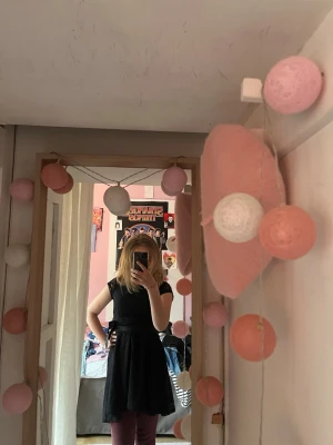 Svart spetsklänning med rosett - Snygg svart kortklänning med spetsdetaljer och markerad midja med bred rosett. Klänningen är ärmlös och har en feminin siluett, perfekt för dig som gillar en klassisk look med lite extra detalj. Materialet är spets och polyester. Ena hällan som man ska ha bandet i är sönder men det funkar ändå galant! 🌟