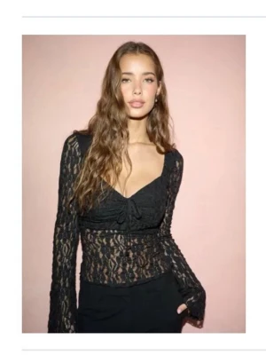 Svart spetsblus från Nelly - En så snygg långärmad lace topp från Nelly i helt nyskick! Den är seetrough överallt förutom vid bysten och har en knytdetaöj i fram! Aldrig använd😍