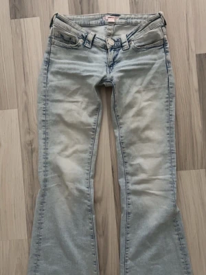 Ljusblå bootcut jeans från Gina14+ - Säljer ett par ljusblå bootcut jeans från Bik Bok med klassisk femficksdesign och låg midja. Jeansen har en snygg tvättad look och är tillverkade i mjukt denimtyg med stretch för extra komfort. Perfekta för en avslappnad och trendig stil. Lite slitna längst ner men inget man tänker på, annars jättefina💗🩷
