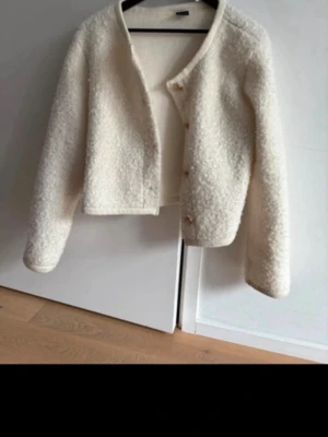 Krämvit teddy cardiganjacka - Mysig krämvit cardiganjacka i teddy-material med rund halsringning och knappar framtill. Jätte fin till sommaren eller våren. Använd 1 gång 