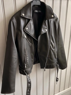 Skinnjacka från Zara - Säljer denna skitsnygga trendiga skinnjacka ifrån Zara!  Den är brun/oliv-färgad. Croppad och har silvriga dragkedjor med bälte!😍 (Den finns inte tillgänglig att köpa längre på deras hemsida) Aldrig använd bara testad & inga defekter. Säljer pga att den inte riktigt passade mig och min stil.  Nypris-700kr Vid intresse eller andra frågor är det bara att höra av er!💚 OBS- köparen står för frakten!