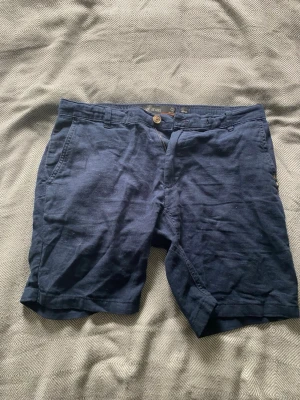 Blå shorts från Indicode Jeans - Mörkblå shorts från Indicode Jeans med klassisk passform. Tillverkade i bomull och har dragkedja och knapp framtill. Perfekta för sommaren och enkla att matcha med olika stilar.