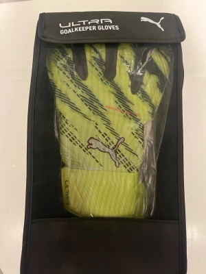 Puma Ultra målvaktshandskar gul - Säljer ett par schyssta Puma Ultra målvaktshandskar i neon-gult med svarta detaljer och Puma-logga. Handskarna har bred kardborrestängning vid handleden och är designade för bästa grepp och komfort på planen. Perfekta för dig som vill sticka ut i målet.