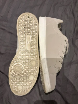 Beige stepside skor stl 46 - Säljer ett par stilrena beige sneakers med vit sula och matchande beige skosnören. Skorna har en clean och enkel design utan synliga loggor, perfekt för dig som gillar en minimalistisk look. Tillverkade i syntetmaterial med lågt skaft och klassisk snörning. Använda en gång
