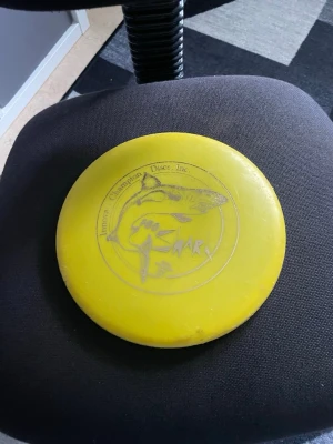 Två discgolfdiscar Shark & Link - Säljer två discgolfdiscar: en gul Innova Champion Discs Shark med hajmotiv och en blå Discmania Evolution Link Putter. Båda är tillverkade i slitstark plast och har tydliga tryck på ovansidan. Perfekta för dig som vill utöka din discgolfarsenal.