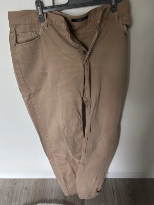 Beige chinos från Emilio - Säljer ett par klassiska beige chinos från Emilio. Byxorna har rak passform, fem fickor och bälteshällor. Tillverkade i mjukt bomullsmaterial som ger en skön känsla och stilren look. Perfekta för dig som vill ha ett par enkla och snygga chinos.