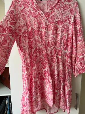 Rosa blommig kortklänning från Zara - Supersöt kortklänning från Zara i vitt och rosa med blommigt mönster. Klänningen har v-ringning, trekvartsärm och volangdetaljer nedtill. Perfekt för sommarens alla tillfällen och tillverkad i ett lätt och luftigt material.STORLEKEN XXL MEN PASSAR S SOM LUFTIG