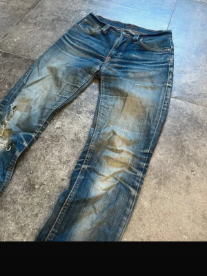 Sjuka slitningar nudie thinn finn - Säljer ett par blå jeans med slitningar och hål på vänster ben. Jeansen har en klassisk femficksmodell, normal midja och raka ben. Färgen är tvättad blå med tydliga slitningar och ljusare partier för en cool, använd look. Årsmodell 2003, w29 l34. Pris kan diskuteras vid snabb affär