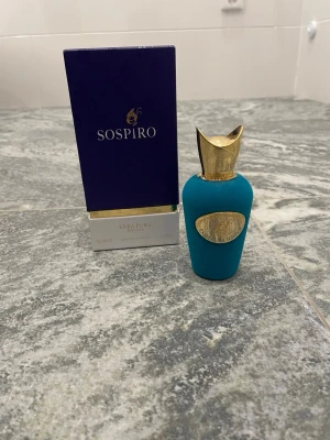 Sospiro Erba Pura parfym 100ml - Lyxig parfym från Sospiro, modellen Erba Pura. Flaskan är klädd i sammetsliknande turkost material med gulddetaljer och elegant guldfärgad kork. Medföljande  ask. Volymen är 100 ml. Perfekt för dig som gillar exklusiva dofter. Skulle tippa att det finns runt 98ml kvar i flaskan då jag bara andvänt den 2-3 gånger. Det finns en liten skada vid toppen av flaskan se bild. 