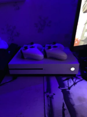 Vit Xbox One S med två handkontroller - Säljer en stilren vit Xbox One S med två matchande vita trådlösa handkontroller. Konsolen har en slimmad, rektangulär design med ventilerad ovansida och klassisk Xbox-logga. Perfekt för gaming och streaming. + runt 15 spel kom privat för mer info