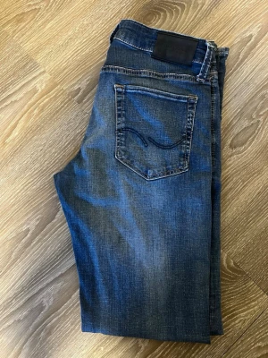 Blå jeansshorts från Jack & Jones - Snygga blå jeansshorts från Jack & Jones med klassisk femficksdesign och knappgylf. Shortsen har en normal passform och är tillverkade i bomull med en lätt tvättad look. Perfekta för en avslappnad stil under varmare dagar.