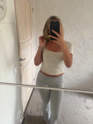Vit croppad topp med fyrkantig ringning - Snygg vit croppad topp med fyrkantig ringning och korta ärmar. Toppen har en tight passform och är perfekt att styla med höga byxor eller kjol. Enkel och stilren design som passar till många olika looks.
