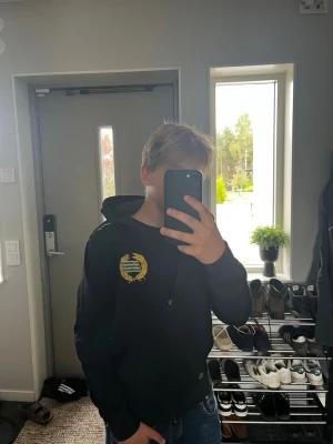 Svart  Hammarby hoodie med dragkedja från Craft - Svart hoodie från Craft med dragkedja och huva. Har ett gult och grönt klubbmärke på bröstet samt två fickor framtill. nypris 549kr Tillverkad i mjukt material som känns skönt mot huden. Perfekt för chill dagar eller träning. Modell: 160cm. Vid frågor skriv och priset kan alltid diskuteras 
