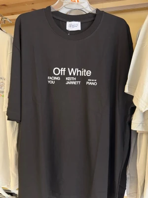 Svart Off White t-shirt Keith Jarrett - Säljer en svart t-shirt från Off White med tryck fram och bak. Framsidan har vit text med 'Off White' och Keith Jarrett-referenser. Baksidan har stort grafiskt tryck med konstmotiv och text. Klassisk passform och rund hals. Perfekt för dig som gillar streetwear och unika prints.