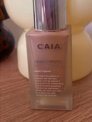 CAIA Dewy Drops Serum Foundation 20W - Foundation från CAIA i nyansen 20W. Dewy Drops Serum Foundation ger en naturlig, daggig finish och innehåller vitamin E och glycerin för återfuktning och antioxidanter. Kommer i en stilren glasflaska med silvrig pump och rymmer 30 ml.