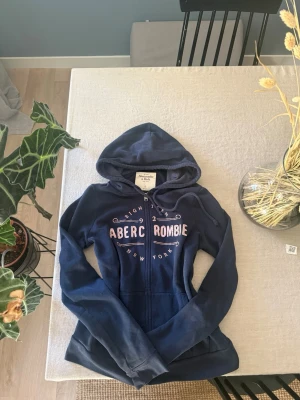 Mörkblå hoodie från Abercrombie & Fitch - Snygg mörkblå hoodie från Abercrombie & Fitch med dragkedja.
