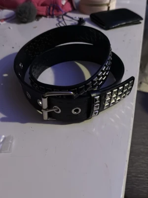 Svart nitskärp - Snyggt svart skärp med silverfärgade nitar och metallspänne. Skärpet har en klassisk form och passar perfekt till jeans eller för att ge outfiten en edgy vibe. Justerbar längd med flera hål för bästa passform. Köpt på SHEIN tyvärr. Skriv om ni vill ha mått eller liknande