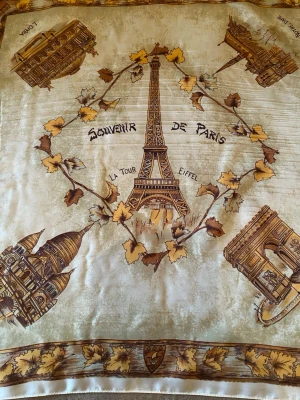 Parissjal med Eiffeltornet och monument - Snygg fyrkantig sjal i beige och bruna toner med motiv av Eiffeltornet, Sacré-Cœur, Triumfbågen och andra Paris-monument. Dekorerad med löv och texten 'Souvenir de Paris'. Perfekt accessoar för dig som älskar Paris.