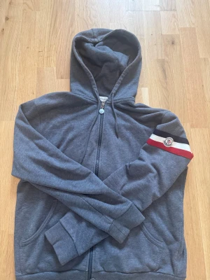 Grå moncler hoodie  - Grå moncler hoodie från Merch sweden (kvitto sista bild). Det är en XL i storleken men den sitter som en M/L . Jag som är 189 ungefär känner att den sitter perfekt, lite lite lite kort i höjden. Den är i topp skick. Använts men använts väl.