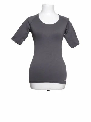 Mörkgrå tight t-shirt från Triumph - En stilren mörkgrå t-shirt från Triumph med tight passform och korta ärmar. Tillverkad i ett mjukt och stretchigt material som sitter skönt mot kroppen. Perfekt för en clean och enkel look.