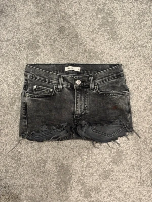 Svarta jeansshorts med slitningar - Snygga svarta jeansshorts  med slitna kanter och fransar. Klassisk femficksmodell med knapp och dragkedja framtill. Perfekta för en cool och avslappnad stil.