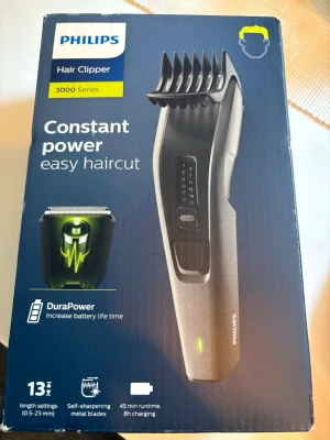 Philips hårtrimmer 3000 Series - Philips hårtrimmer från 3000 Series med 13 längdinställningar (0,5-23 mm), självslipande metallblad och DuraPower-teknik för längre batteritid. Trimmern är svart med detaljer i grått och har en ergonomisk form. Laddningstid är 8 timmar och användningstid 45 minuter. Den är helt ny, bara kartongen som är öppnad.