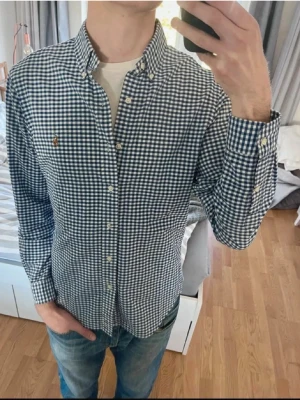 Blårutig skjorta från Polo Ralph Lauren - Klassisk blårutig skjorta från Polo Ralph Lauren med button-down krage och broderad logga på bröstet. Skjortan har vita knappar och lång ärm, perfekt till jeans eller chinos. Tillverkad i mjuk bomull för en skön känsla.