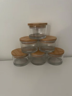 Glasburkar med bambulock, 5-pack - Säljer fem runda glasburkar med snygga lock i bambu. Perfekta för förvaring av småsaker, kryddor eller snacks. Burkarna är genomskinliga och locket har en naturlig träfärg som ger en stilren känsla till rummet.
