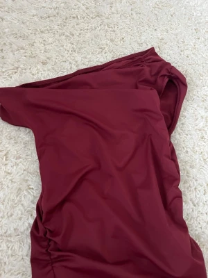 Vinröd axelbandslös klänning Shein - Säljer en vinröd axelbandslös klänning från Shein i storlek XS. Klänningen har en enkel och stilren design med åtsittande passform och är tillverkad i ett mjukt syntetmaterial. Perfekt för dig som vill ha en elegant look.