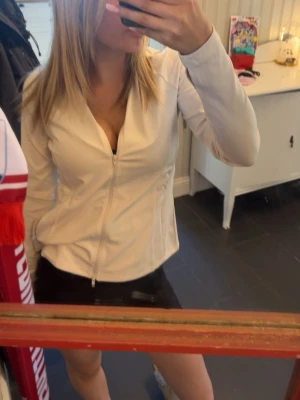 Vit zip-jacka med figurnära passform - Snygg vit jacka med dragkedja framtill och figurnära passform. Jackan har lång ärm och enkel, stilren design som passar till många outfits. Perfekt för dig som gillar en clean och modern look.