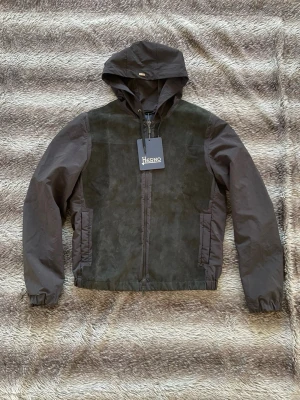 Herno Windbreaker Jacka   - Hej! Säljer nu denna väldigt snygga Herno vindjacka. Passar perfekt till våren och sommarkvällar. Jackan har mocka av getläder detaljer. Jackan är helt ny och kommer med alla tags. Storlek: 50 fits M Nypris: ca 10000kr Säljs för: 3499 kr