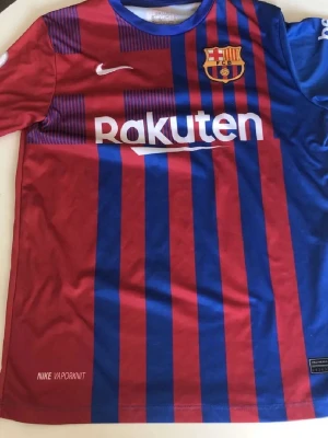 Barcelona matchtröja Nike röd/blå - Säljer en  FC Barcelona matchtröja från  med klassiska röda och blå vertikala ränder. Tröjan har klubbmärke, Nike-logga och Rakuten-tryck fram samt UNICEF-tryck bak. Tillverkad i lätt och ventilerande material, perfekt för fotboll eller träning.