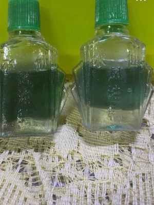 2st  kinesisk olja - Två små flaskor med grön vätska, troligen kinesisk medicinsk olja. Flaskorna är genomskinliga med grön plastkork och har kinesiska tecken ingraverade på glaset. Perfekt för dig som gillar traditionella skönhetsprodukter.  Endast för utvärtes bruk, får ej förtäras.