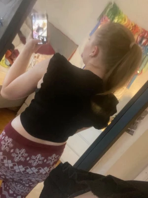 Svart croppad topp med volangärm - Svart croppad topp med korta volangärmar och rund halsringning. Toppen är ribbad och sitter tight mot kroppen, perfekt för en trendig och stilren look.