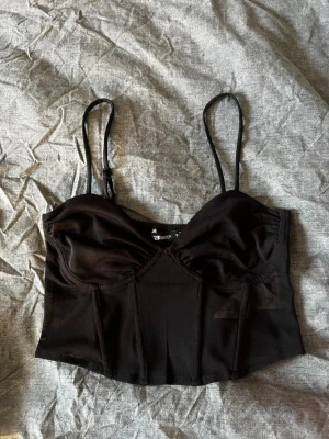 Svart korsettopp  - Är genomskinlig i korsett delen, den är längre framtill än baktill