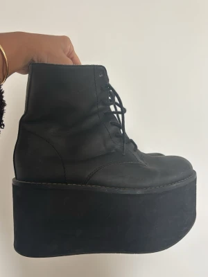 Jeffrey Campbell Svarta platåstövletter med snörning - Unika svarta stövletter med extremt hög platåsula och snörning framtill. Skorna har en rund tå och är tillverkade i ett matt material som ger en cool och edgy look. Perfekta för dig som vill sticka ut och addera höjd till din stil.Jeffrey Campbell x Nasty Gal. Ord pris 2500 kr 