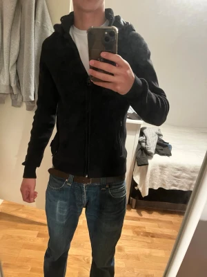 Svart indicode med dragkedja - Säljer en eftertraktad svart indicode zip tröja med avtagbar luva. Den är i storlek xs men sitter lite mer som s. Fint skick och perfekt nu till våren.