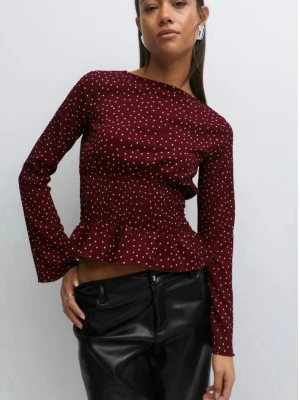 Vinröd prickig blus med volang - Supersnygg vinröd blus med vita prickar och smock i midjan som ger en markerad siluett. Blusen har långa ärmar och en liten volang nertill för extra detalj. Perfekt till både jeans och kjol för en trendig look.