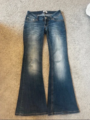 Blå bootcut jeans blaze - Snygga blå bootcut jeans från lager 157 med låg midja och klassisk femficksdesign. Jeansen har slitningar och ljusare partier framtill för en cool vintagekänsla. Tillverkade i denim med stretch för skön passform. storlek xs/short. 